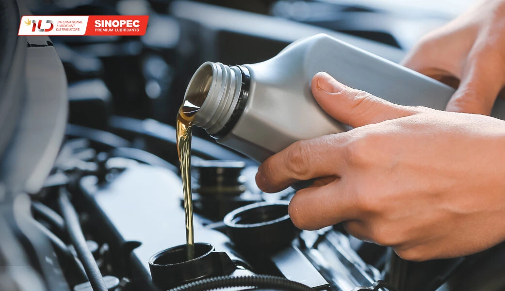 Close-up of motor oil being poured into a car engine, featuring Sinopec branding, representing clean and professional industrial web design for the automotive sector